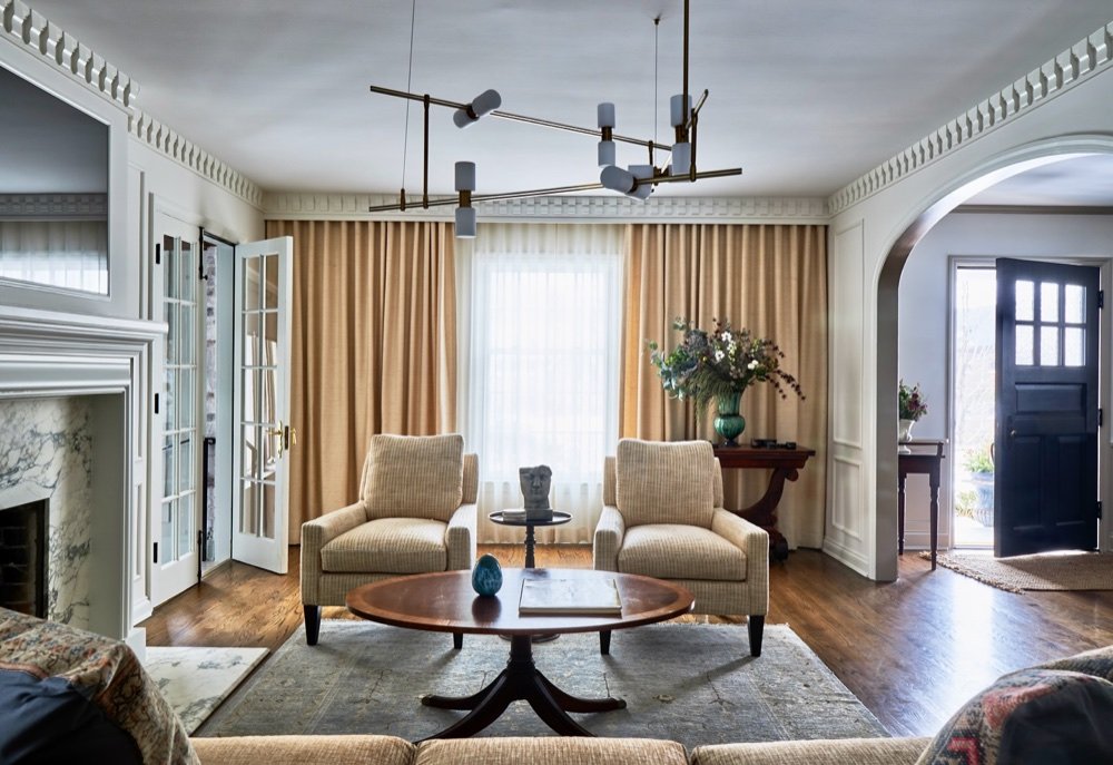 Living room with brass chandelier, drapery, marble fireplace, luxury renovation and interior design by Martire Custom Homes