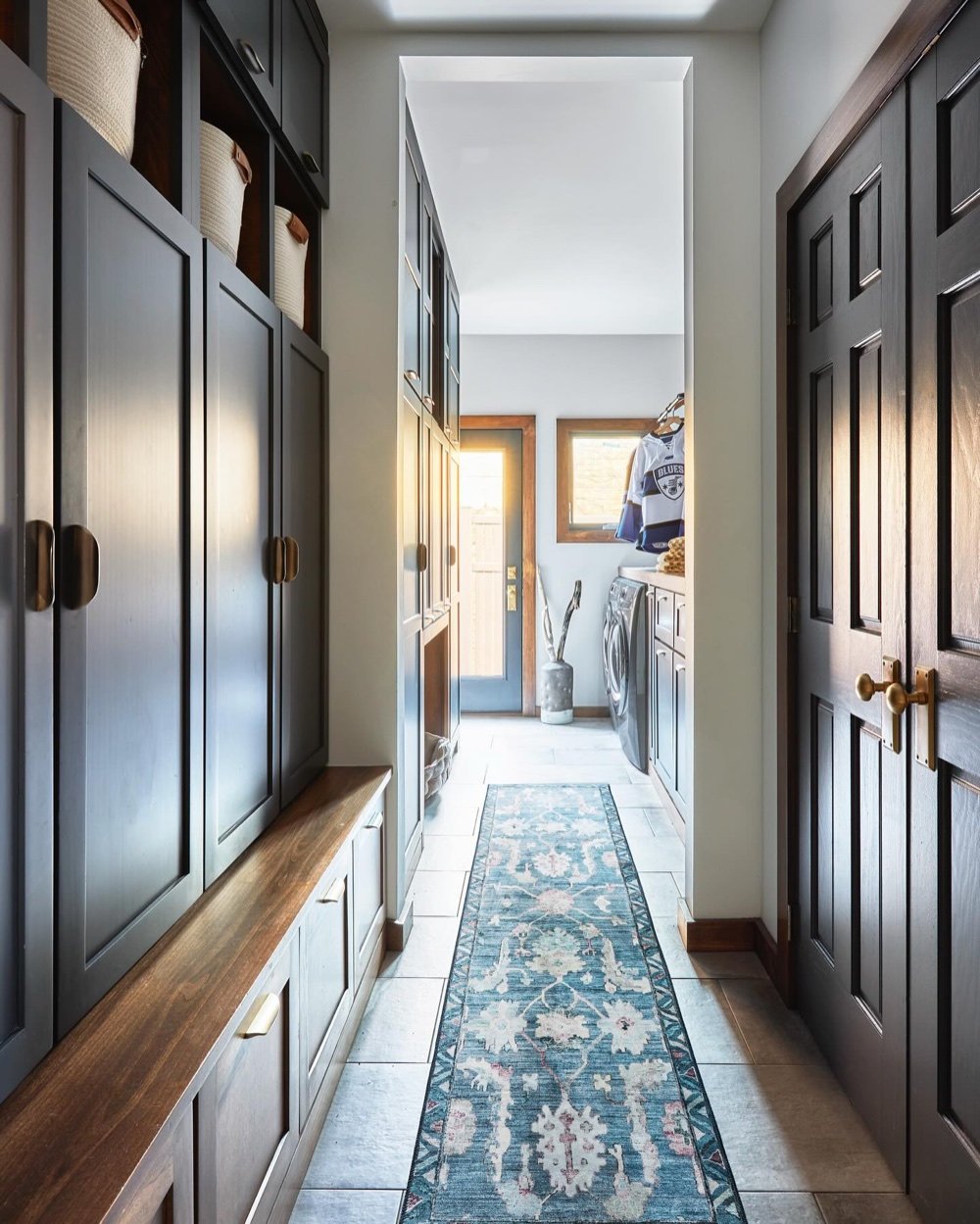Mudroom/laundry hall with navy cabinetry and runner rug, luxury renovation and interior design by Martire Custom Homes