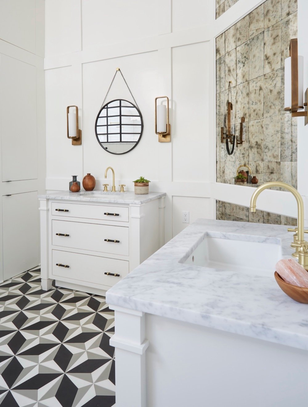 Primary ensuite vanity wall with Carrara marble tops, brass gooseneck faucets, chain-hung round mirror and floor-to-ceiling antique mirror inlay by Martire Custom Homes