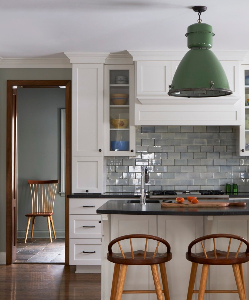 Kitchen with vintage green industrial shop lantern pendant, glazed gray-blue subway tile, honed black counters, and spindle stools, by Martire Custom Homes