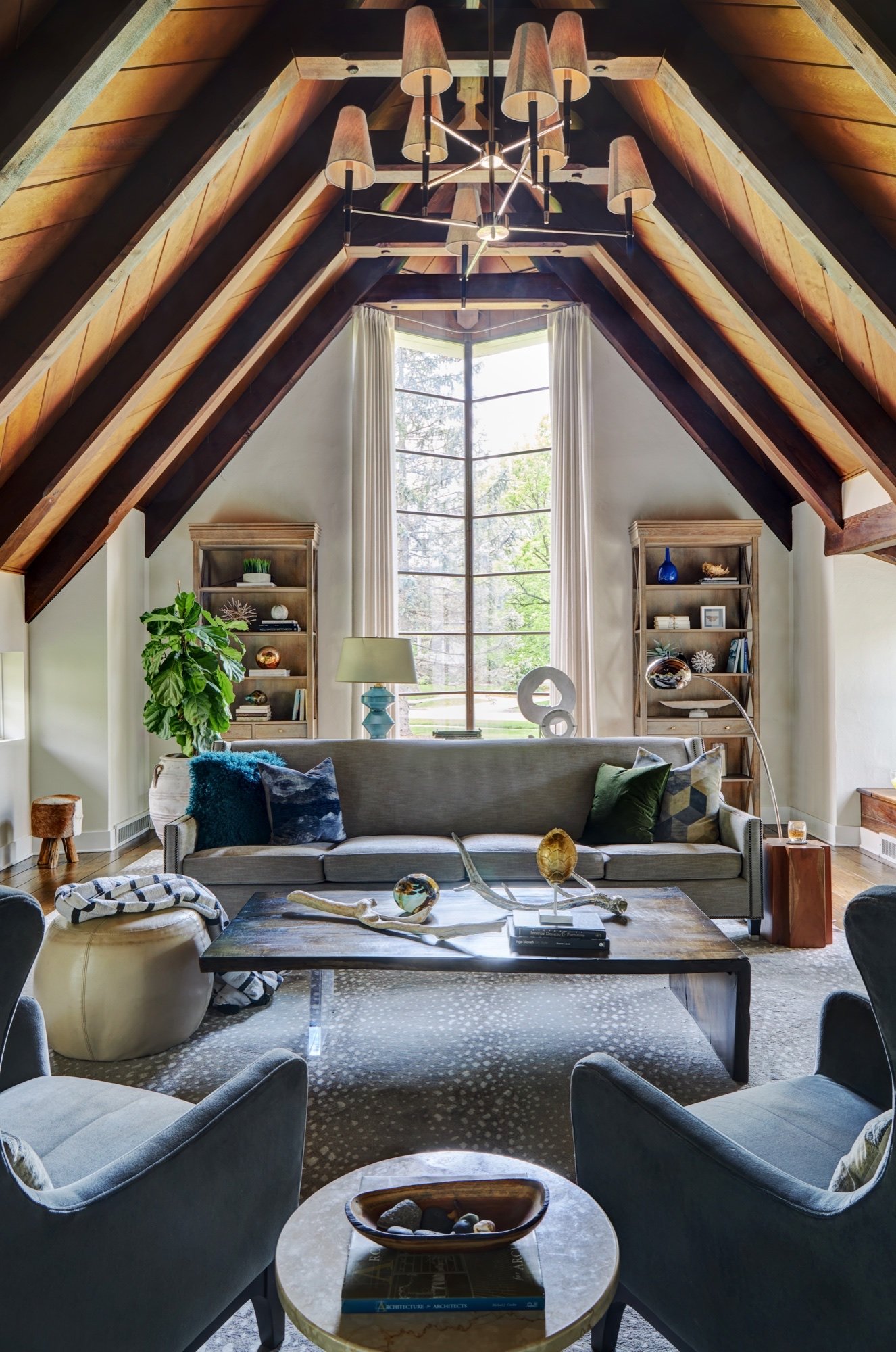 Eye-level view of a vaulted great room with restored dark timber rafters, wood plank ceiling and a tall window with chevron mullions, by Martire Custom Homes