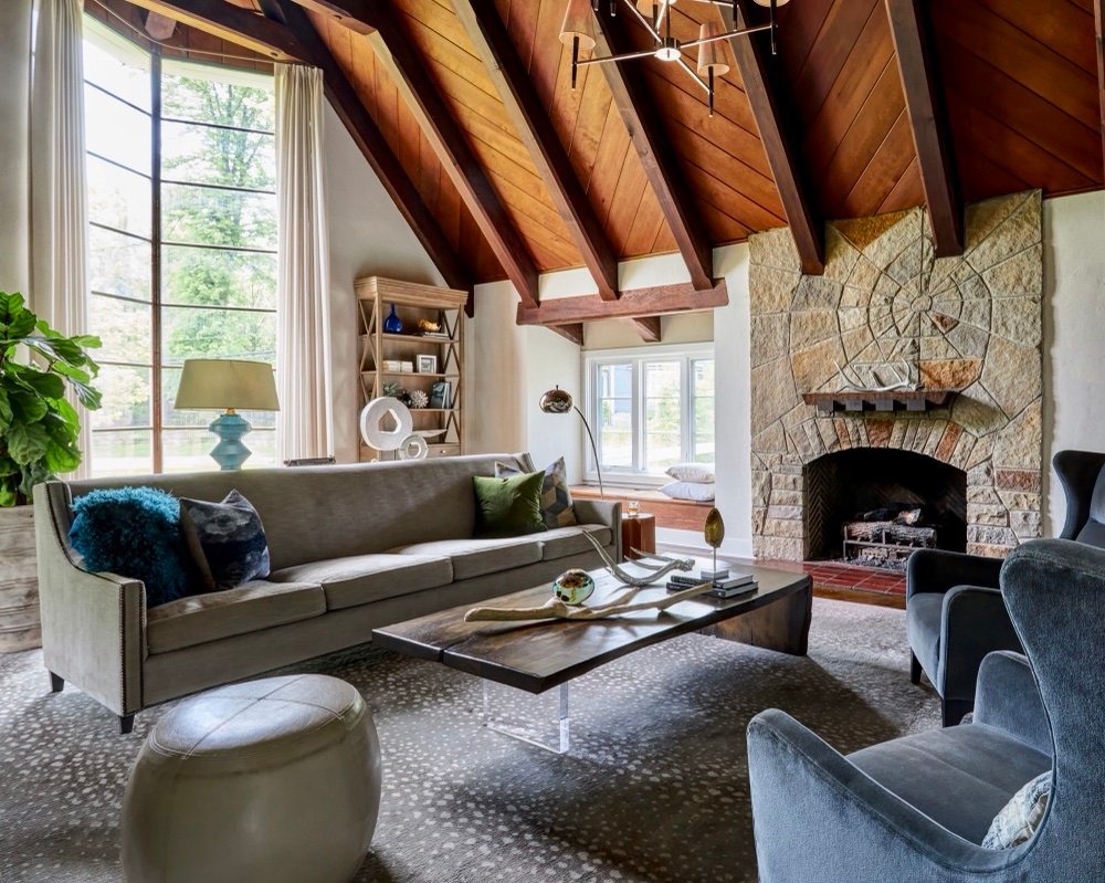 Restored 1940s living room with original stone fireplace laid in a spider-web motif, herringbone firebox and wood plank ceiling with exposed beams, by Martire Custom Homes
