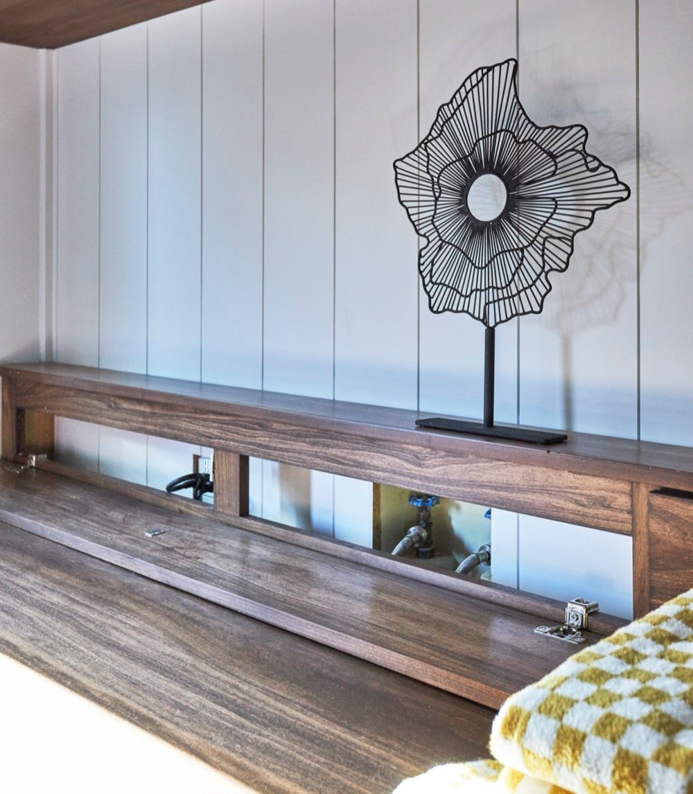 Walnut folding counter with its hinged shelf open, revealing concealed washer and dryer hookups behind custom millwork, by Martire Custom Homes