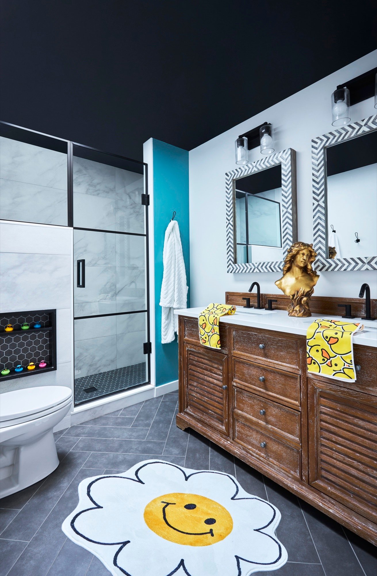 Children's bathroom with black painted ceiling, teal accent wall, marble-look shower surround, honeycomb tile niche and playful daisy rug, by Martire Custom Homes