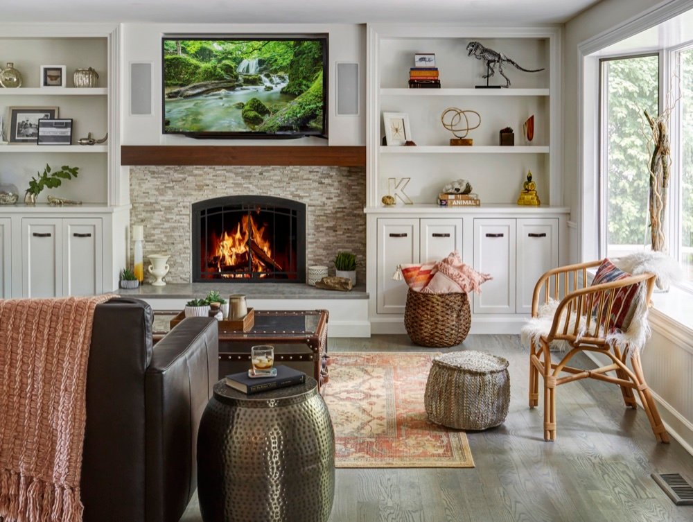 Family room with a stacked-stone tile fireplace, chunky walnut box mantel and painted built-in shelving beside a bright corner window, by Martire Custom Homes
