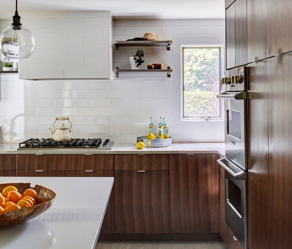 Range wall with a white subway-tiled hood, stainless open shelving, professional gas cooktop and natural quartzite perimeter counters, by Martire Custom Homes